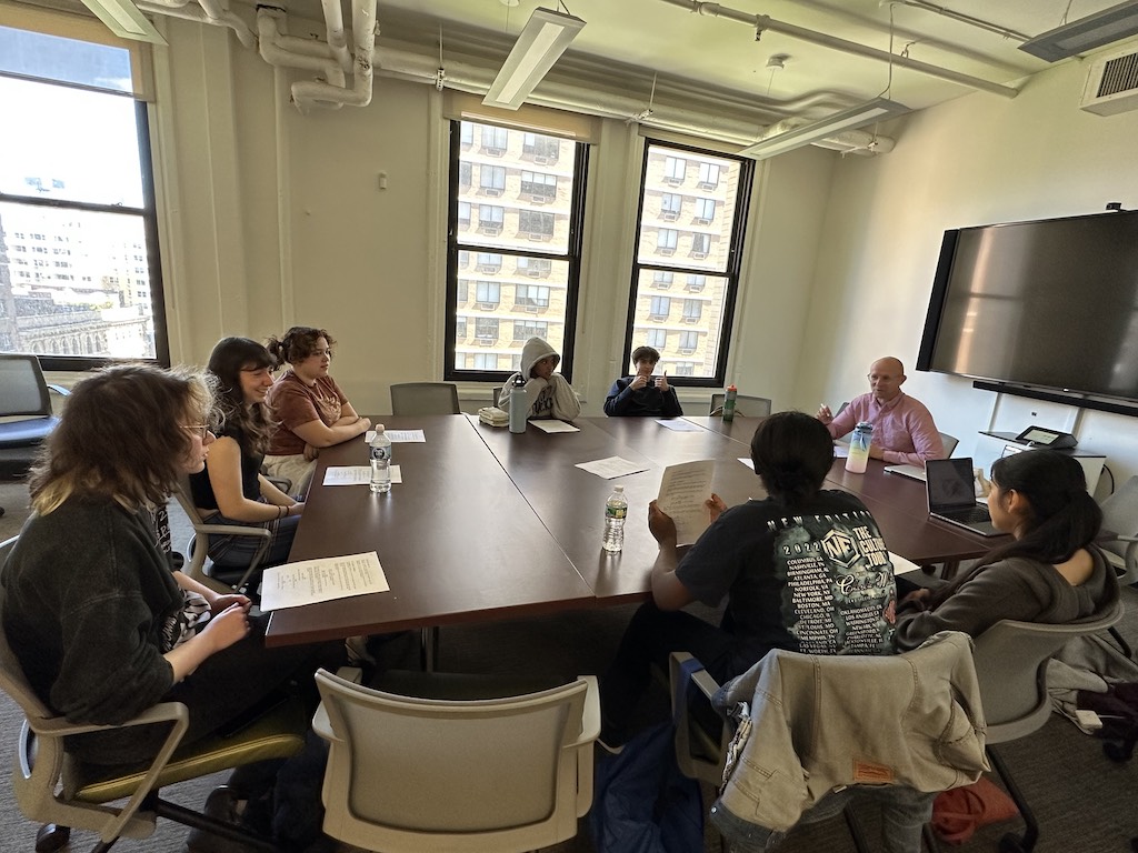 Students sit around a large conference table during a Future Dramatic Writers class.